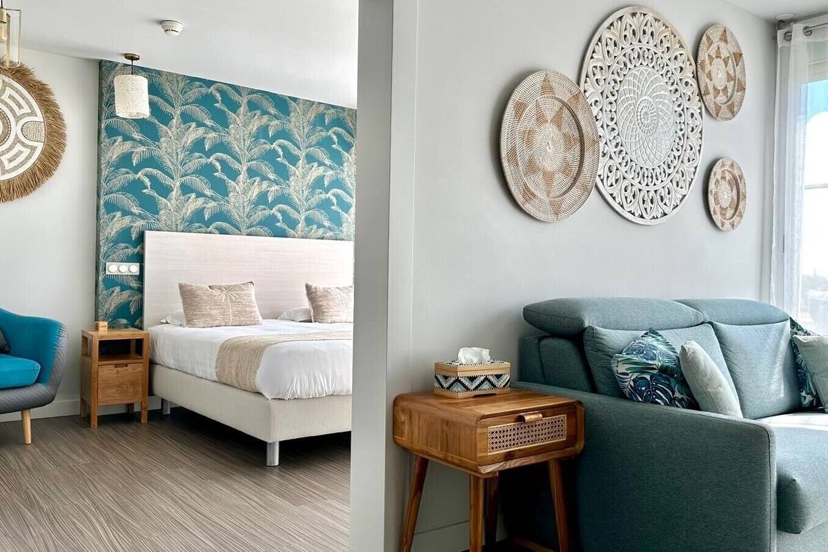 A bedroom with a bed, a blue armchair, a nightstand, and decorative wall art.