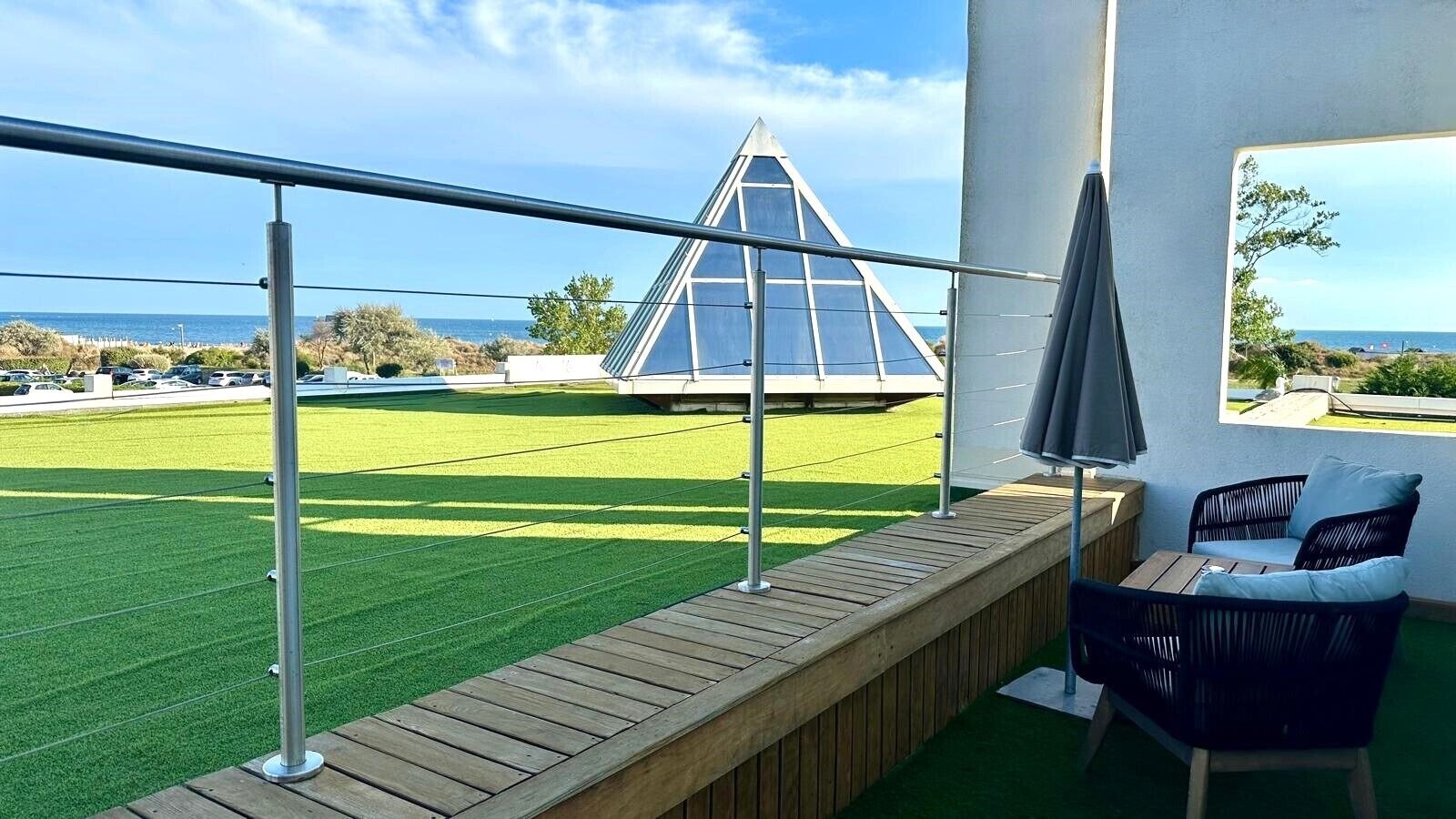 A balcony with a view of a green field and a pyramid-shaped structure.