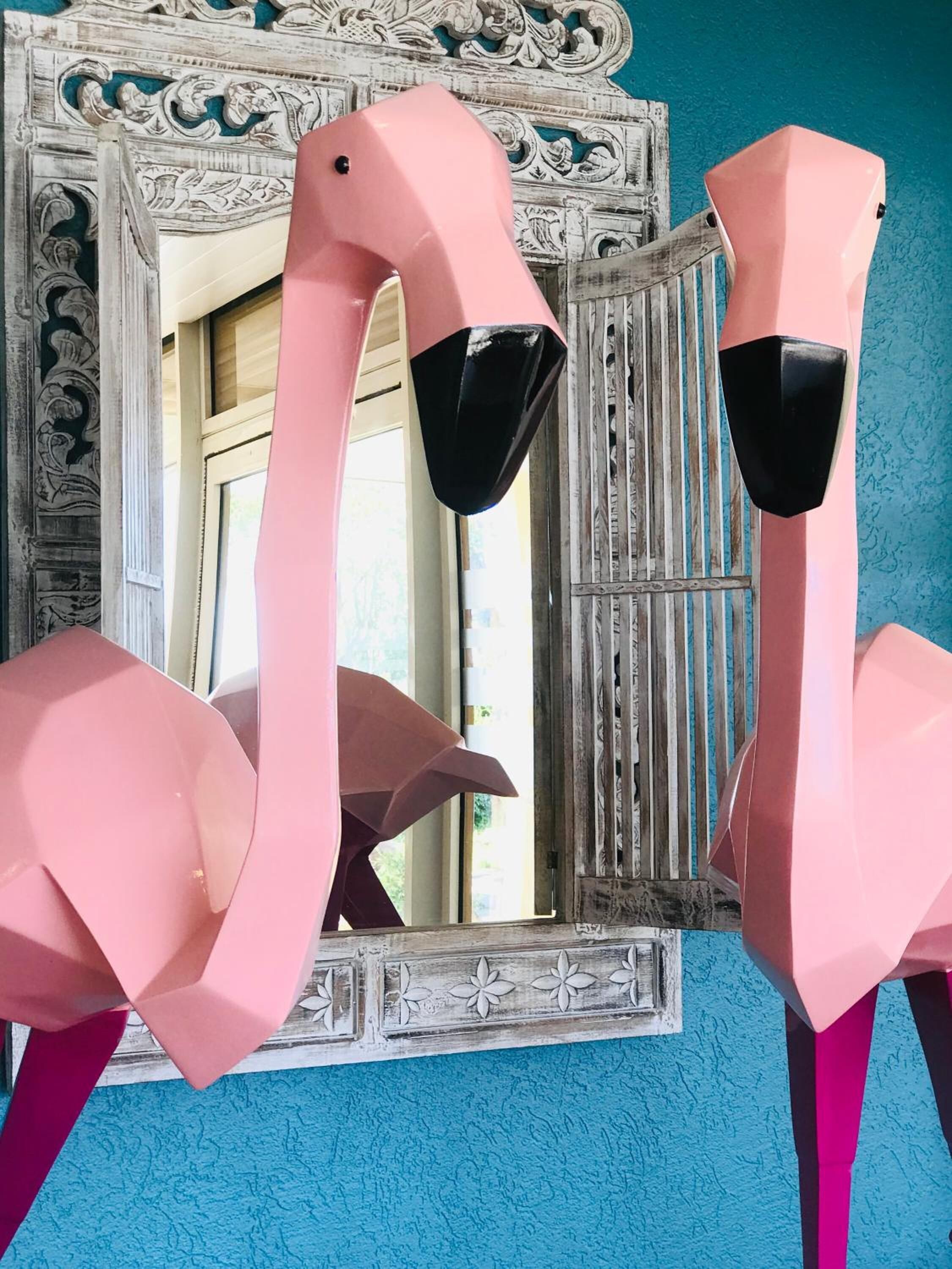 A room with a large mirror and two pink flamingo sculptures.