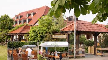 Un edificio de estilo europeo tradicional con techo de tejas rojas, zona de estar al aire libre y un cartel que indica jardín de cerveza.