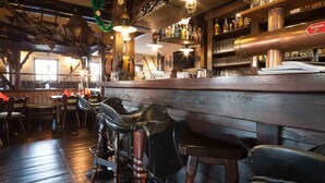 A bar area with wooden furniture, metal stools, and a bar counter with bottles and glasses. - Hotel 3 Linden (Leipzig)