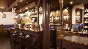 A bar area with wooden furniture, a cash register, and shelves with bottles. - Hotel 3 Linden (Leipzig)
