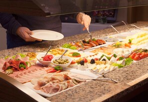 Un buffet proposant une variété de plats, notamment des viandes, des fromages et des légumes.