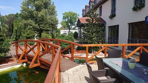 A wooden bridge over a pond with a table and chairs on the right. - Hotel 3 Linden (Leipzig)