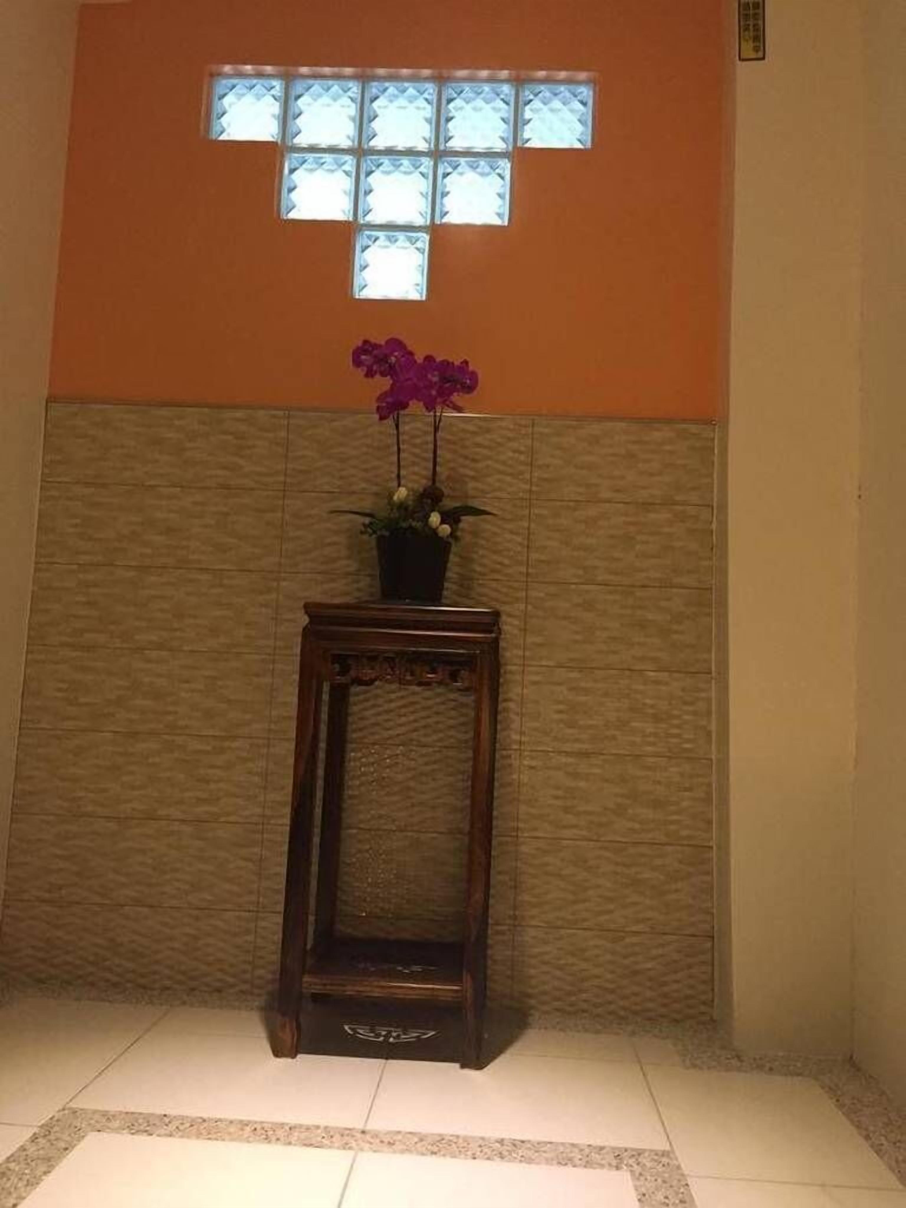 Une petite table en bois, sur laquelle est posée une plante en pot, et une fenêtre au-dessus.