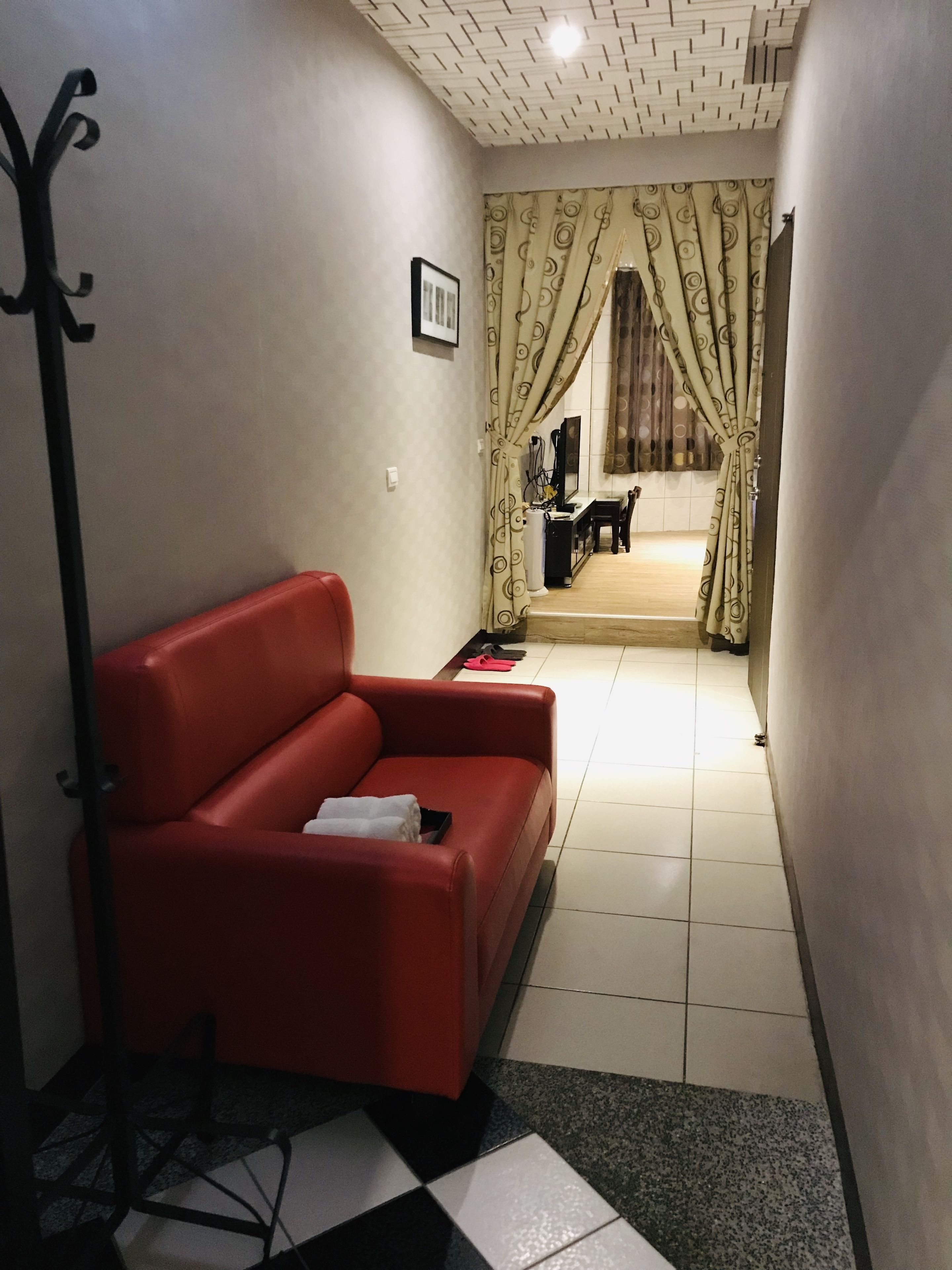 A living room with a red sofa, a black and white patterned rug, and a black floor lamp.
