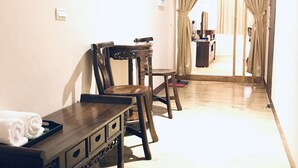 A hotel room with a wooden dining table, two chairs, a small cabinet, and a view through a doorway. - Orange House B&B Juifen (New Taipei City)