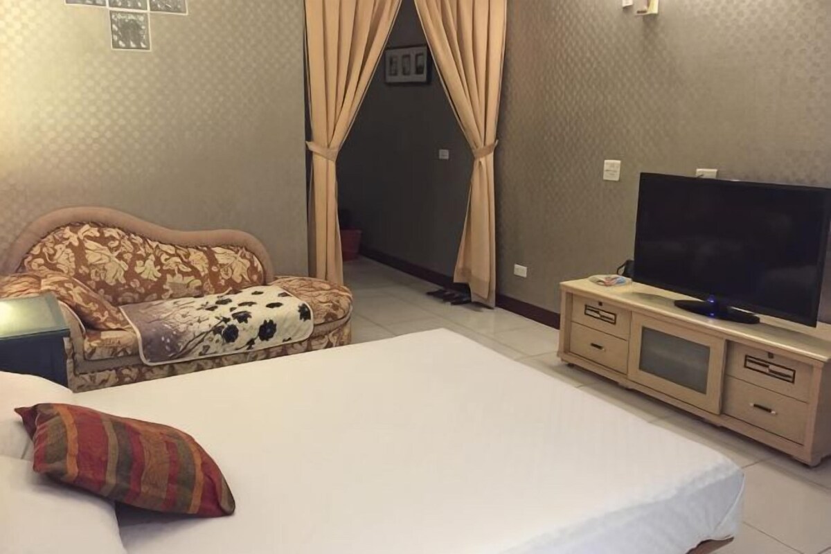 A hotel room with a bed, a sofa, a television, and a cabinet.