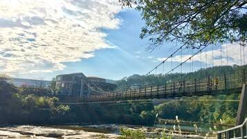 A suspension bridge over a river with a building in the background.