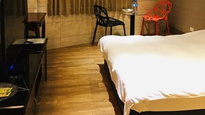 A hotel room with a bed, a desk, a chair, an air conditioning unit, and a television. - Orange House B&B Juifen (New Taipei City)