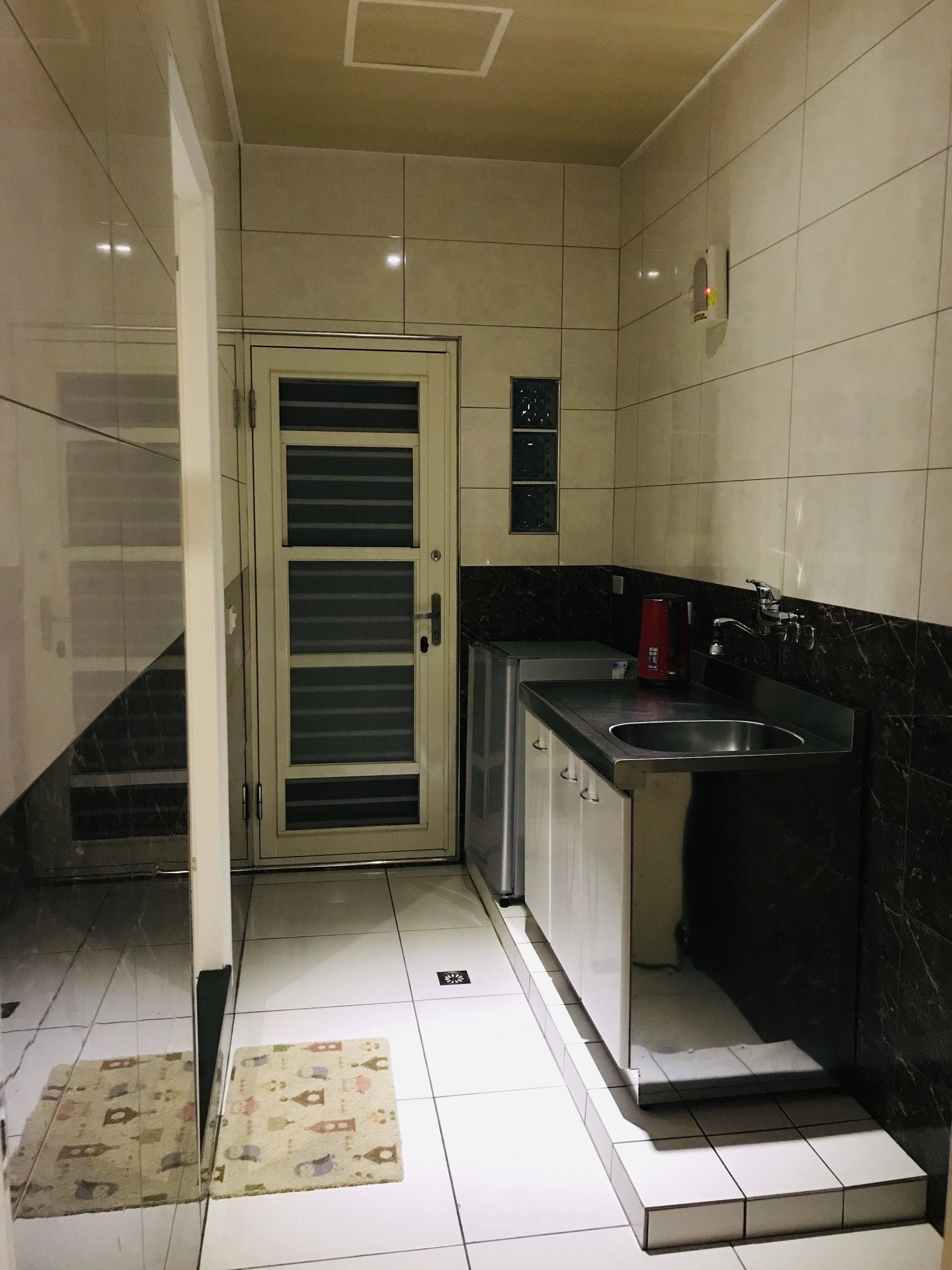 A small kitchen with a sink, a coffee maker, and a door with a frosted glass panel.