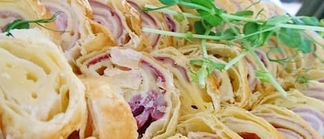 A plate of rolled pastry with red onion and cheese filling, garnished with green herbs.
