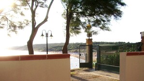 Une vue d’une plage avec une porte et des arbres au premier plan.