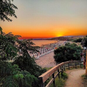A beach with a wooden walkway leading to the water, surrounded by greenery. - Residence la Darsena (Isola di Capo Rizzuto)