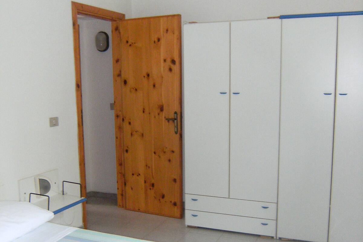 A bedroom with a bed, a wardrobe, and a door.