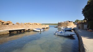 Un canal bordé de bateaux amarrés, de murs en pierre et sous un ciel dégagé.