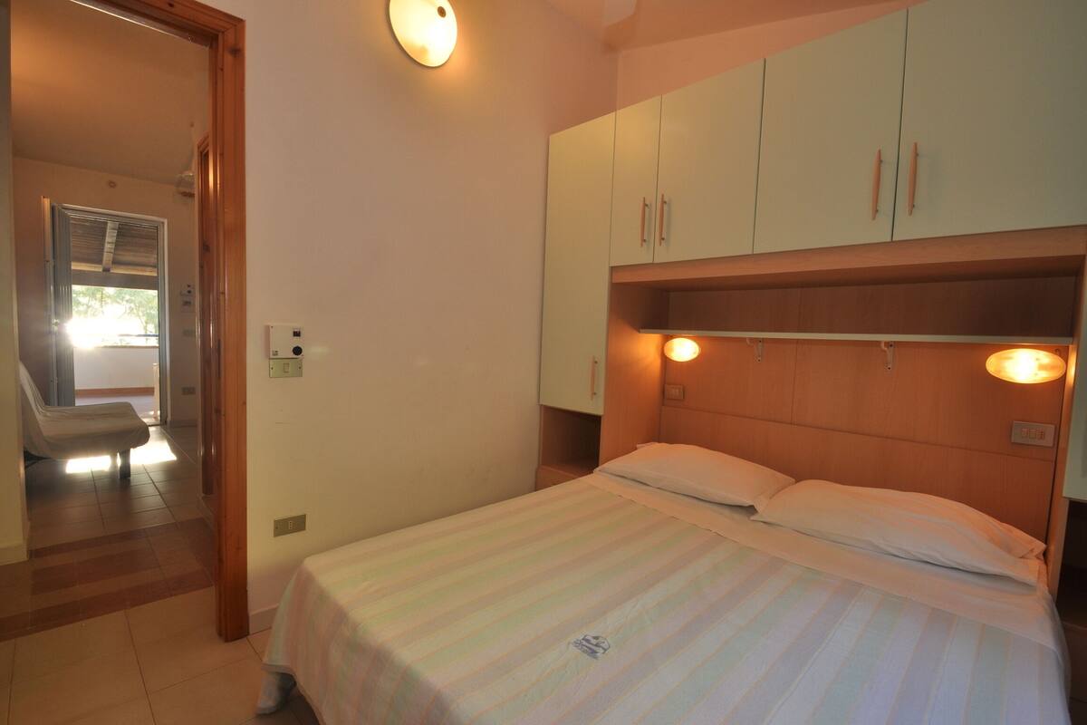 A bedroom with a bed, wooden headboard, and cabinets.