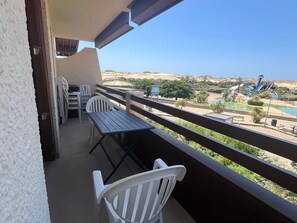 A balcony with a table and chairs, overlooking a pool and water park.