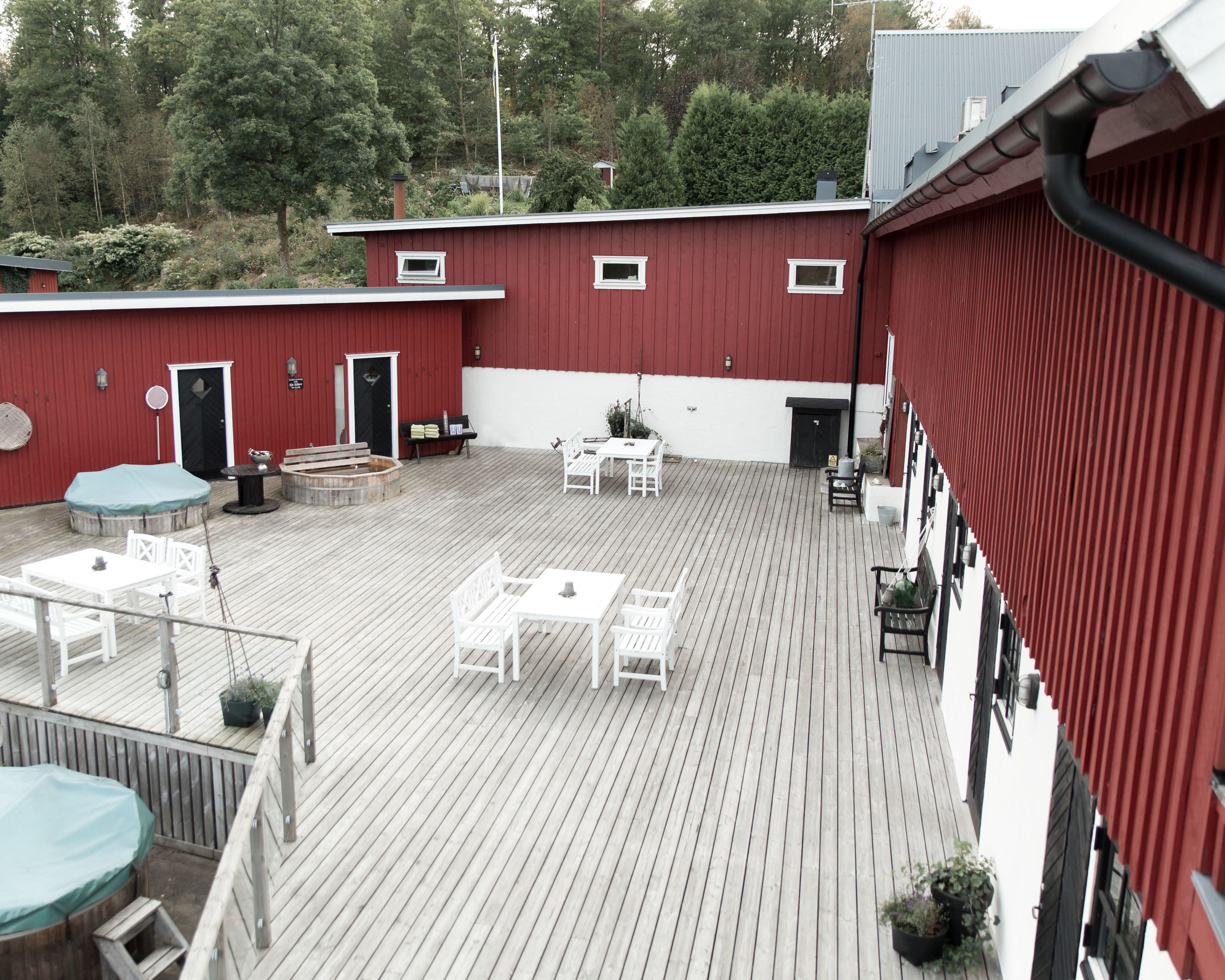En takförsedd uteplats med vita möbler, en eldstad och ett litet bord med en växt.