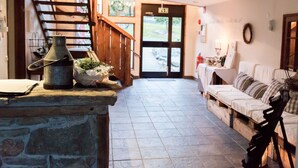 A cozy living room with a stone fireplace, a wooden staircase, and a white sofa. - Sju Sjöar Konferens (Oxnevalla)