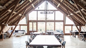 An attic-style room with a high ceiling, large windows, a central table, and multiple chairs. - Sju Sjöar Konferens (Oxnevalla)