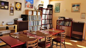 A room with a wooden table and chairs, surrounded by bookshelves filled with books and records. - Fossatún Country Hotel (Borgarbyggd)