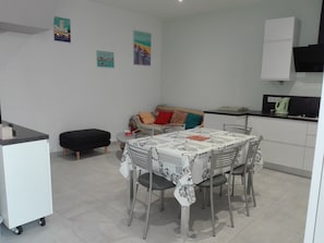 Un espace de vie compact comprenant une table à manger, des chaises, un canapé et un coin cuisine.