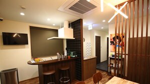 Uma cozinha compacta com bancada, piso de madeira e televisão na parede.