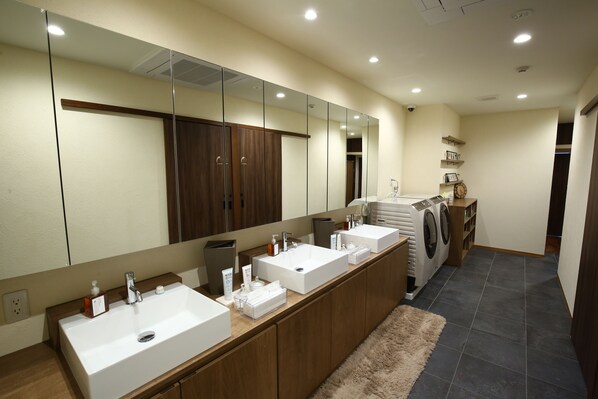 A modern bathroom with two sinks, a large mirror, and a built-in washing machine.
