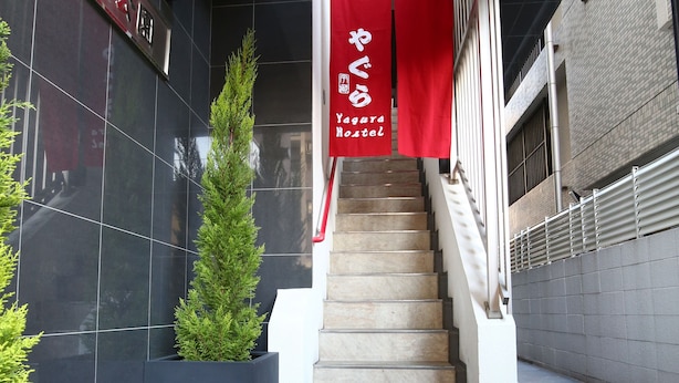 Escada que leva a um edifício com um letreiro vermelho e um vaso de planta ao lado.