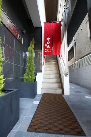 A staircase leading to a building with a red banner and a potted plant beside it.