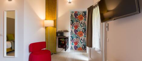 A modern living room with a red chair, a flat-screen TV, and a floral-patterned wall.