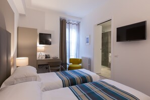 Habitación de hotel con dos camas, un escritorio, una silla, un televisor y zona de ducha.