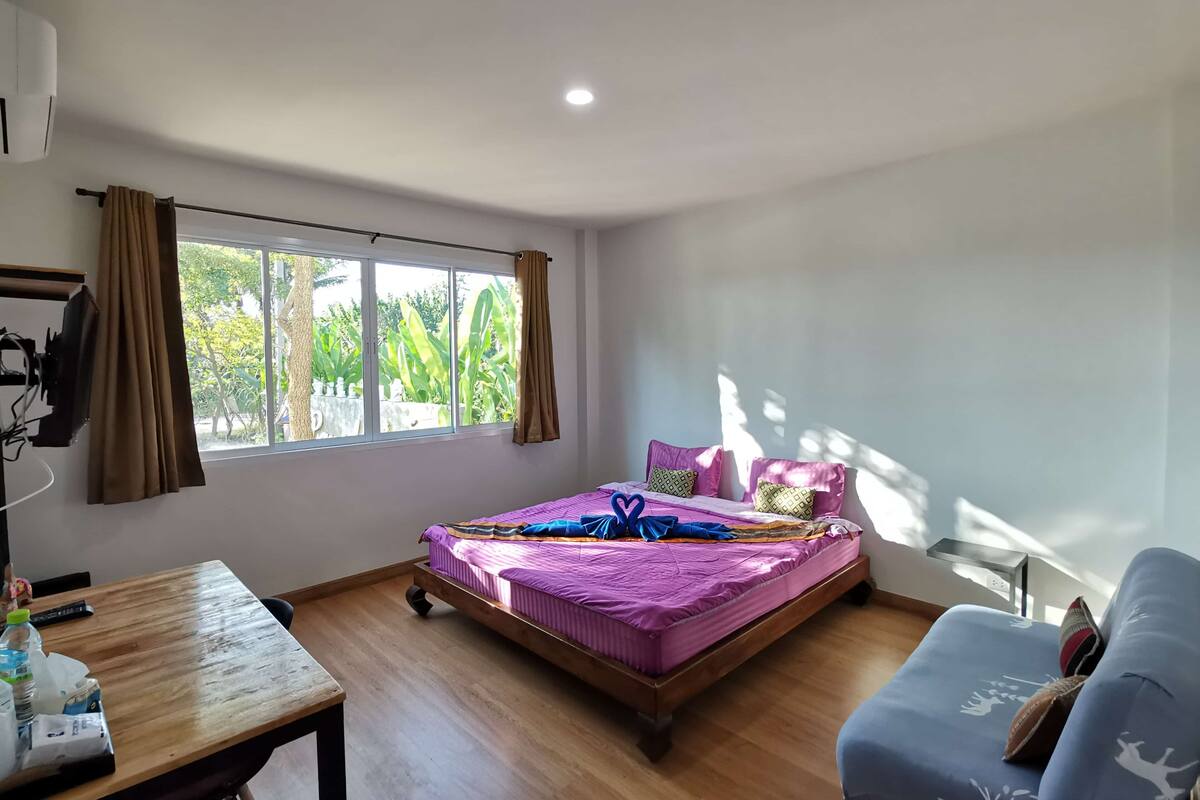 Una habitación con cama, una mesa y una ventana.