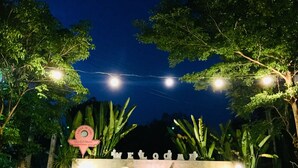 A sign for "Panida Goodwill Resort" with a large, illuminated signboard surrounded by lush greenery and string lights. - Panida Goodwill (Nong Hin)