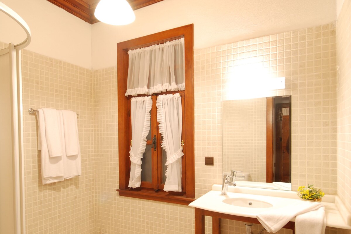 Ein Badezimmer mit Holzboden, einem weißen Waschbecken mit Spiegel und einer Duschkabine.