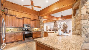 Una cocina amplia con gabinetes de madera, encimeras de granito y una pared decorativa de piedra.