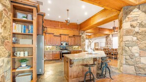 Una cocina amplia con armarios de madera, una isla central y taburetes de bar.
