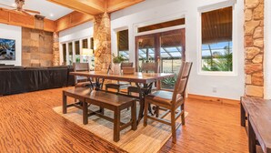 Un salón amplio con techo de madera, paredes de piedra y ventanas grandes que ofrecen vistas al exterior.