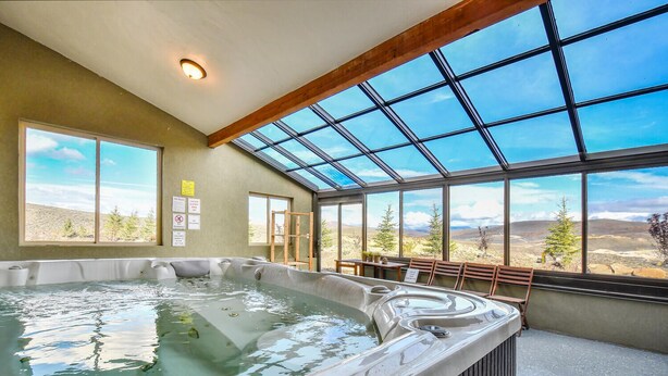 Un jacuzzi con vistas a un paisaje montañoso a través de amplios ventanales.
