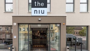 Une entrée d’immeuble avec une enseigne indiquant « the niu » et une porte en verre.