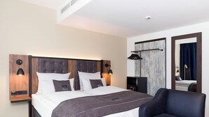 Une chambre d’hôtel moderne dotée d’un grand lit, d’un coin salon et d’un miroir.