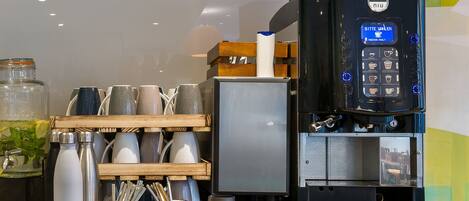 A coffee machine with a digital display, a coffee grinder, and a mug rack with various cups and mugs.