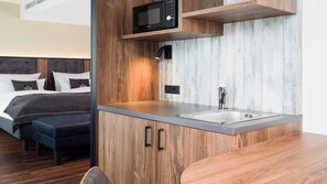 A compact kitchenette with a microwave, sink, and wooden cabinetry. - Holiday Inn - the niu, Saddle Furth by IHG (Fuerth)