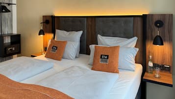 A hotel room with a large bed, two bedside tables, a wooden headboard, and a wall-mounted lamp.