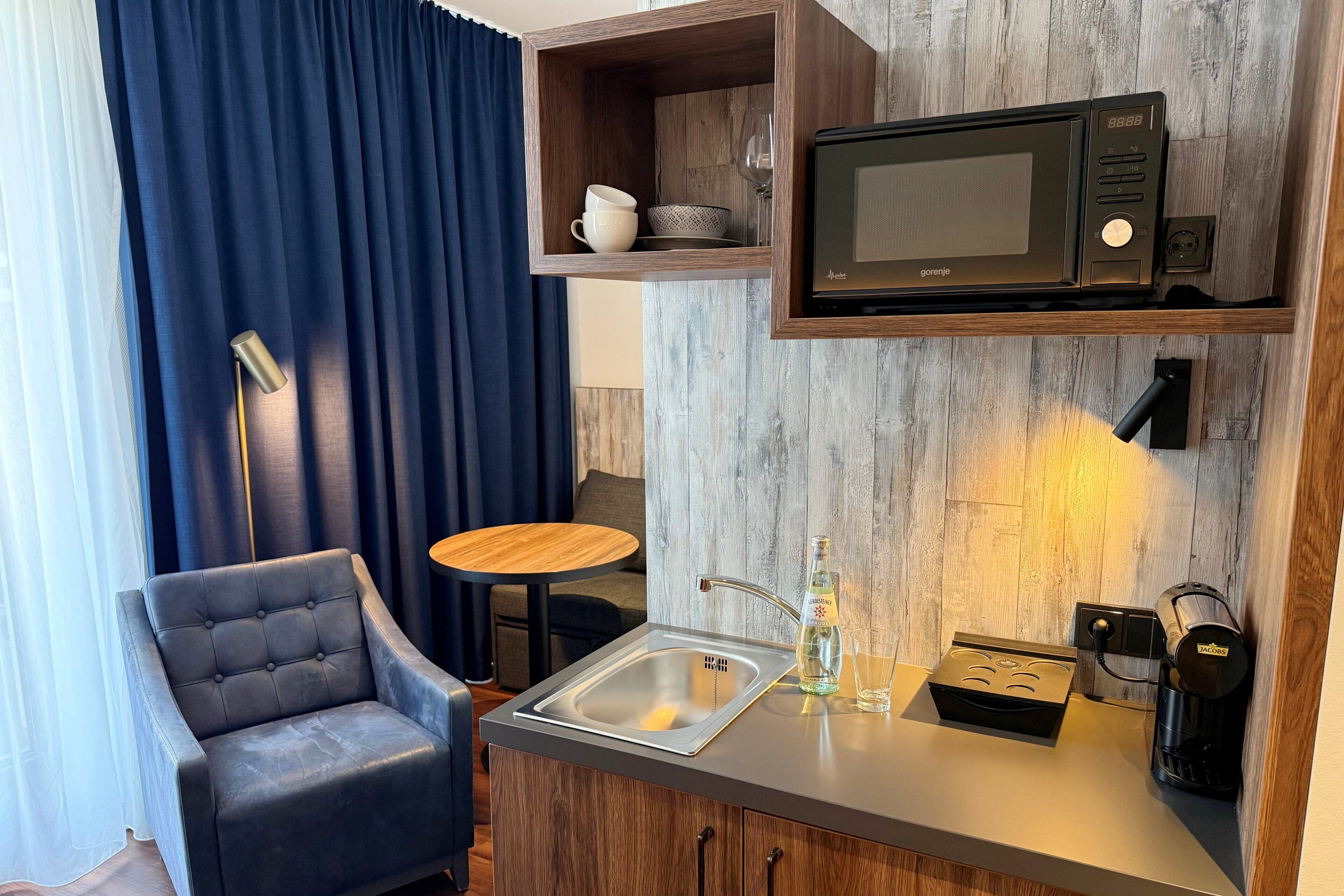 A compact kitchenette with a microwave, coffee maker, and a small sink.
