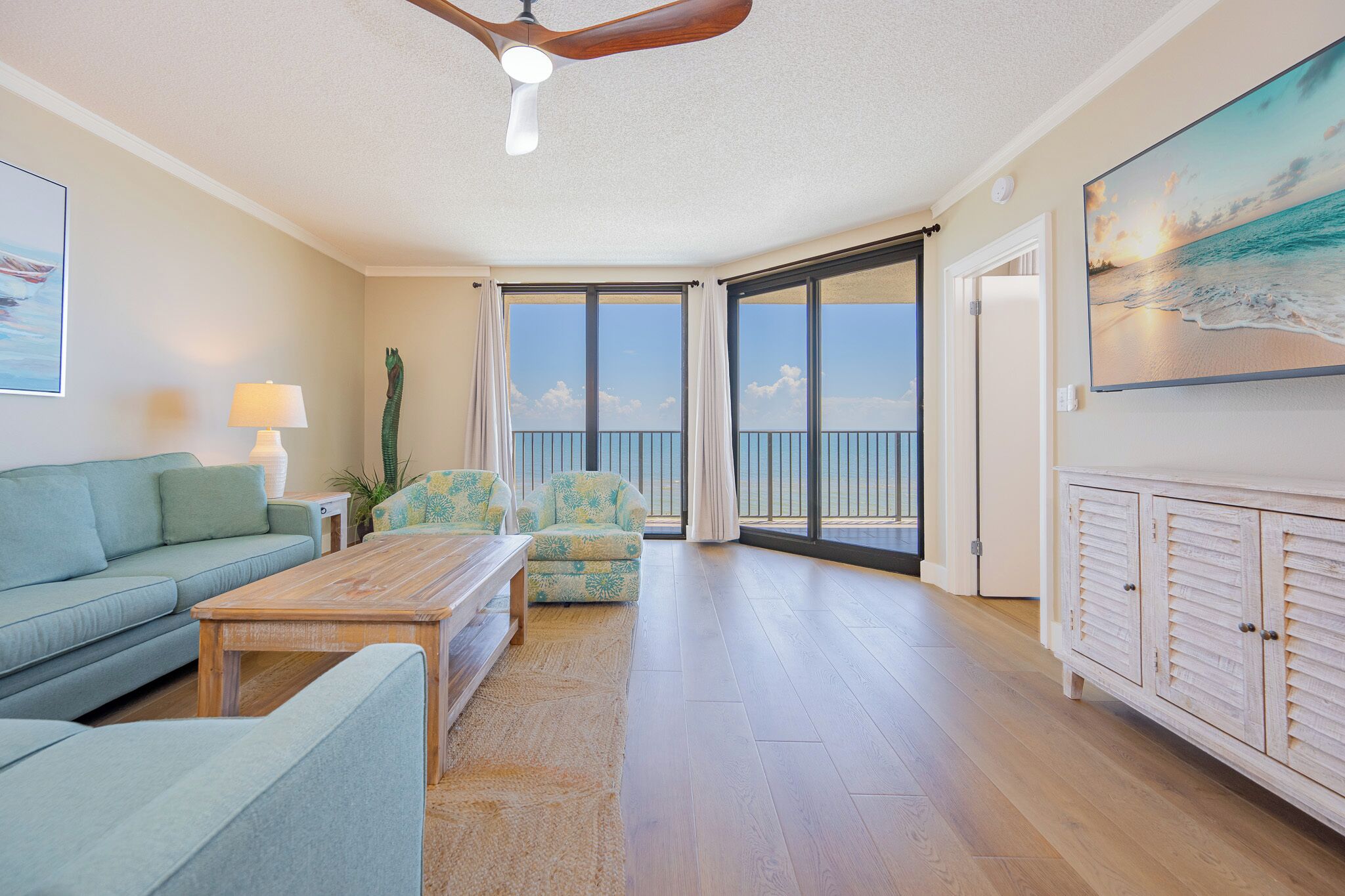 Amplia sala de estar con sofá, una mesa de centro, una silla y un balcón con vista al mar.