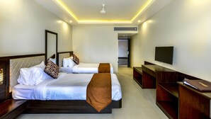 Habitación de hotel con dos camas, un televisor y un escritorio.