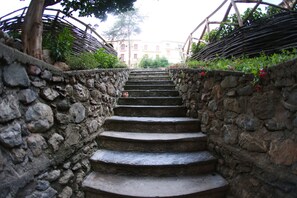 Un escalier en pierre menant à un bâtiment, entouré de verdure et délimité par une clôture en bois.