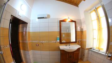 Un baño con techo de madera, un lavamanos, un espejo y una ventana con cortinas.